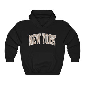May include: Black hooded sweatshirt with the text "NEW YORK" in brown letters.