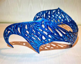 May include: A blue, intricate, 3D printed crown with a delicate, lacy design. The crown is made of a lightweight material and has a curved shape.