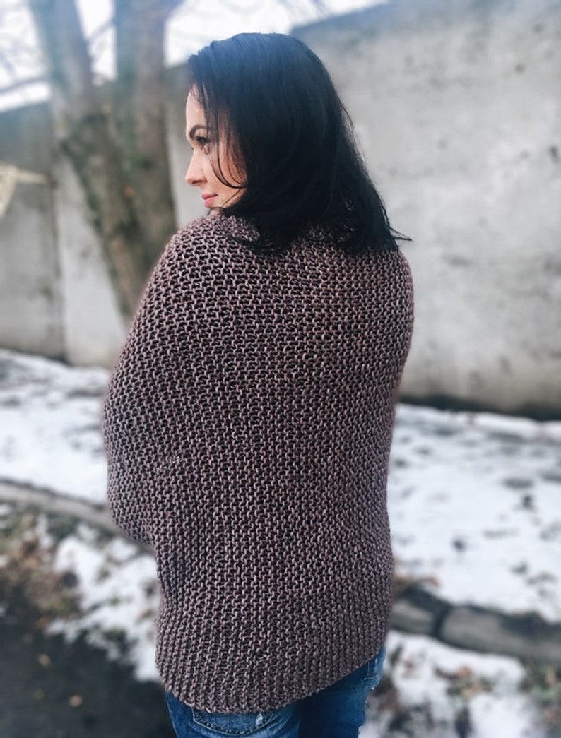 May include: A brown knitted sweater with a loose fit and a high neck.