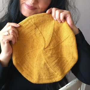 Peut inclure: Un béret en tricot jaune avec un motif circulaire. Le béret est fait d'un fil doux et texturé.