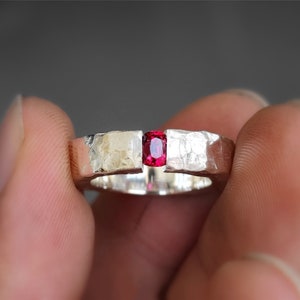May include: A silver ring with a hammered finish and a red gemstone set in the center.