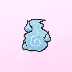 May include: A light blue embroidered patch in the shape of a stylized flame with a white swirl design. The patch has a black border and is set against a pink background. The flame design includes three teardrop shapes.