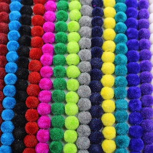 Può includere: Una varietà di passamanerie a pompon colorati, ogni filo presenta un colore diverso. I colori includono arancione, marrone, blu, nero, rosso, rosa, verde, verde lime, grigio, blu navy, giallo, verde acqua, viola, bianco e rosa.