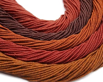 Könnte beinhalten: Nahaufnahme einer Sammlung von Perlen in Braun-, Orange- und Rottönen. Die Perlen sind in einem geschichteten Muster angeordnet, das eine visuelle Textur erzeugt.