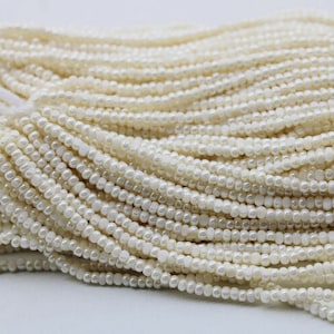 Peut inclure: Un brin de perles blanches, parfait pour la fabrication de bijoux ou l'artisanat. Les perles sont petites et de taille uniforme, créant un look délicat et élégant.