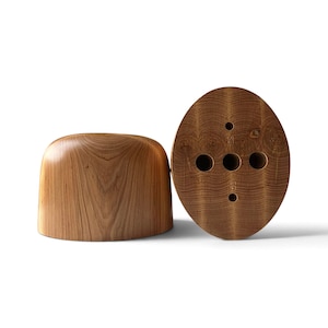 May include: Two smooth, light brown wooden objects with visible grain patterns. One is a rounded, dome-shaped piece, while the other is an oval-shaped piece featuring five circular holes and the engraved number 60 on its surface.