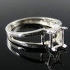 May include: Silver ring setting with a rectangular bezel for a gemstone. The setting has a split shank design.