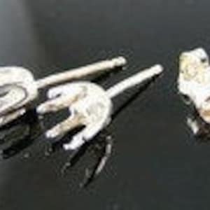 May include: A pair of silver earring posts with a unique design. The posts are made of metal and have a smooth finish.