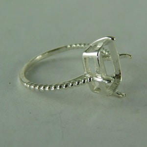 May include: Silver ring setting with a twisted band and a square shaped bezel for a gemstone.