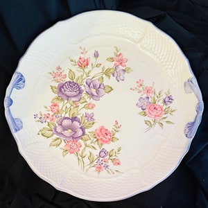 May include: White ceramic serving platter with a raised rim and a floral design. The design features pink, purple, and green flowers on a white background.