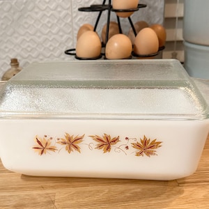 May include: White rectangular baking dish with a glass lid. The dish has a brown and gold floral design around the edge.