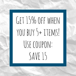 May include: A white rectangular sign with a dark blue border displays the text "GET 15% OFF WHEN YOU BUY 5+ ITEMS! USE COUPON: SAVE 15" in black handwritten font. The background is a crumpled white paper texture.