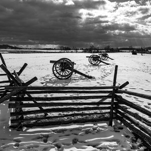 A black and white photo of cannons in the snow at the Gettysburg National Military Park on the field of Pickett's Charge.