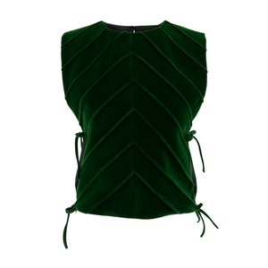 Op de afbeelding: Een mouwloos groen fluwelen topje met een chevron-patroon en strikjes aan de zijkanten.