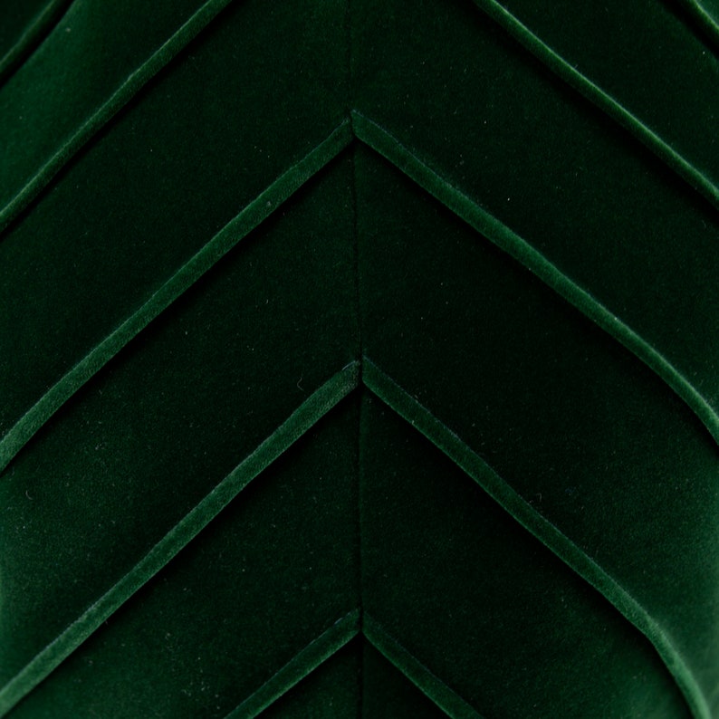Op de afbeelding: Close-up van een donkergroene stof met een chevron-patroon. De stof heeft een zachte, fluweelachtige textuur.