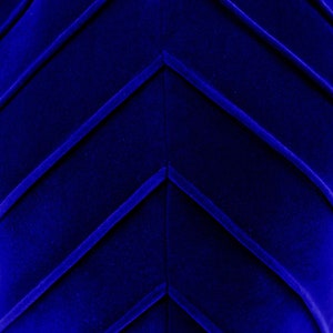 Op de afbeelding: Close-up van een diepblauwe stof met een chevron-patroon. De stof heeft een zachte, fluweelachtige textuur.