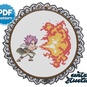May include: Cross stitch pattern featuring a cartoon character with pink hair and a yellow and red fire effect. The pattern is in a white embroidery hoop with a black lace trim.