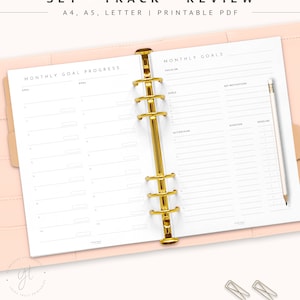May include: A printable monthly planner with a pink cover and gold rings. The planner includes sections for monthly goal progress, monthly goals, focus on, key motivations, action plan, duration, and deadline.