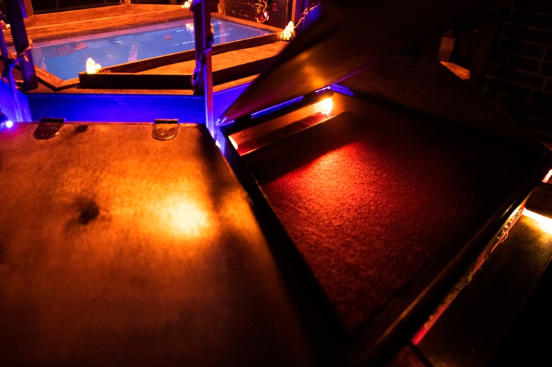 May include: A wooden box with a red velvet interior. The box is open and the velvet is illuminated by a warm light.