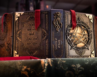 May include: A set of three leather-bound books with ornate gold detailing and red ribbon bookmarks. The books are titled "Secrets of the Witch" and "The Book of Shadows".