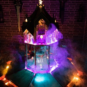 May include: A dark wooden gothic-style structure with a purple and blue light emanating from the base. The structure is surrounded by smoke and has a small book with the text "W4A5" on the top level.