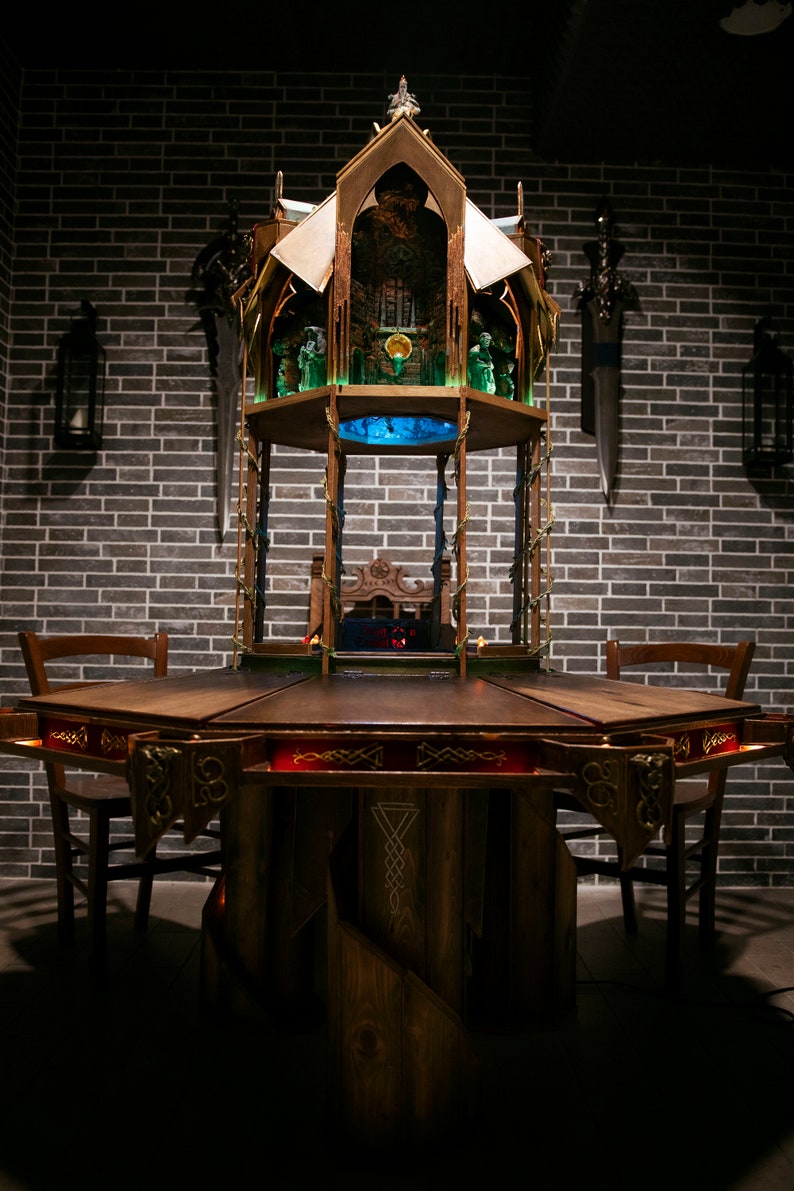 May include: A dark wooden table with a carved design and a red inlay. The table is surrounded by four chairs and features a decorative wooden structure with a blue light in the center.