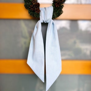 Puede incluir: Una bufanda azul claro con un diseño sencillo. La bufanda está hecha de una tela suave y ligera, perfecta para añadir un toque de color a cualquier atuendo.