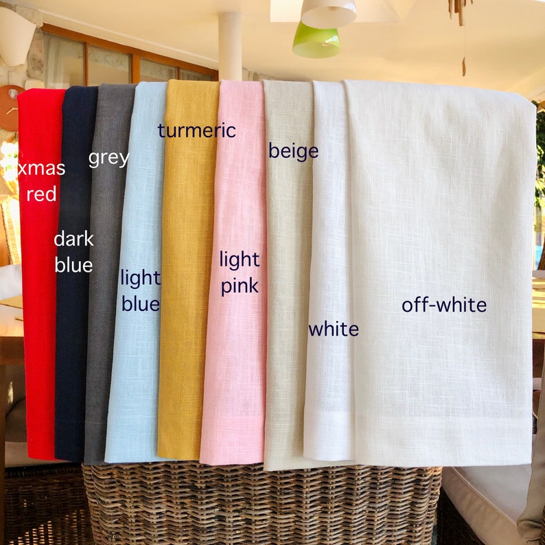 May include: A collection of fabric swatches in various colours, including red, grey, light blue, yellow, pink, beige, white, and off-white. The swatches are arranged in a row, with the names of each colour written on the fabric.