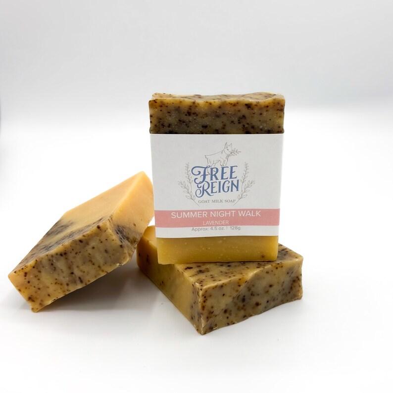May include: Three bars of goat milk soap stacked on top of each other. The top bar has a label that reads "Free Reign Goat Milk Soap Summer Night Walk Lavender Approx. 4.5 oz. | 128g".