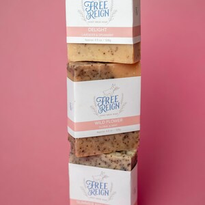 May include: Three bars of goat milk soap stacked on top of each other. The top bar is labeled "Delight Lavender & Spearmint", the middle bar is labeled "Wild Flower Floral & Mint", and the bottom bar is labeled "Summer Night Walk".