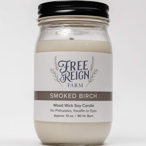 Pu&ograve; includere: Una candela in vetro in un barattolo con un coperchio nero. L'etichetta recita "FREE REIGN FARM" e "SMOKED BIRCH". La candela &egrave; una candela di soia con stoppino in legno senza ftalati, paraffina o coloranti. Ha un peso di circa 13 once e una durata di 80 ore.