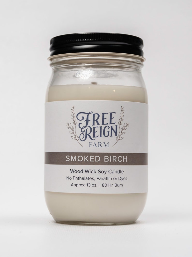 Pu&ograve; includere: Una candela in vetro in un barattolo con un coperchio nero. L'etichetta recita "FREE REIGN FARM" e "SMOKED BIRCH". La candela &egrave; una candela di soia con stoppino in legno senza ftalati, paraffina o coloranti. Ha un peso di circa 13 once e una durata di 80 ore.