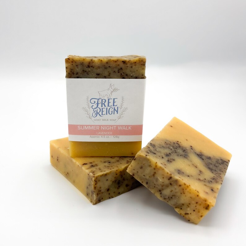 May include: Three bars of yellow and brown goat milk soap with a label that reads "Free Reign Goat Milk Soap Summer Night Walk Lavender Approx. 4.5 oz (128g)"