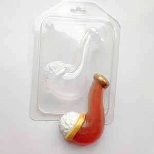 May include: A clear plastic mold for making a red and white pipe. The mold is shaped like a pipe with a bowl and a stem. The pipe is shown in the mold, with a white bowl and a red stem.