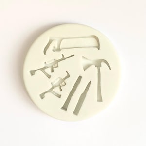 May include: White silicone mould with cutouts of various tools, including an axe, a hammer, a saw, and two guns.