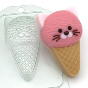 May include: A pink and white cat-shaped ice cream cone mold. The mold is made of clear plastic and has a detailed design.