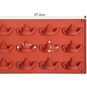 May include: A brown silicone mold with 12 teapot-shaped cavities. The mold measures 10.6 inches by 6.2 inches and each cavity is 2.2 inches wide and 1.3 inches tall.