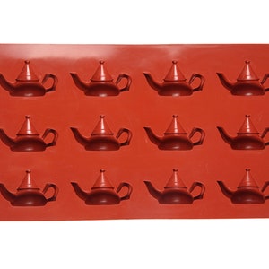 May include: A red silicone mold with 12 teapot-shaped cavities. The mold is designed for making small, decorative teapots.