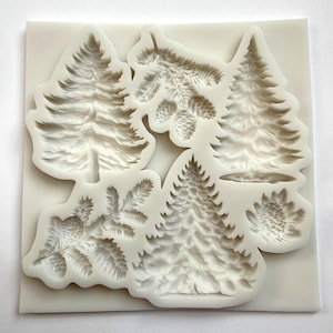 May include: A white silicone mould featuring detailed relief designs of various pine trees, pine cones, and branches. The mould includes several different tree shapes and textures, ideal for crafting projects.