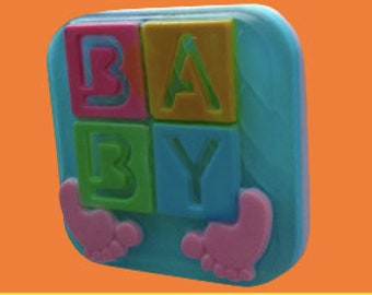 May include: A blue square soap bar with a raised design of four colourful blocks spelling "BABY" with pink baby feet on either side.