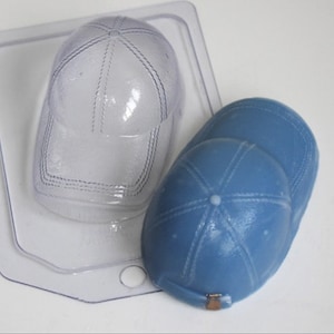 May include: A clear plastic mold for making a baseball cap, next to a blue baseball cap made with the mold.