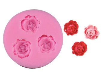 Può includere: Stampo in silicone rosa con tre cavità a forma di rosa. Tre decorazioni a forma di rosa rossa e rosa sono mostrate accanto allo stampo.