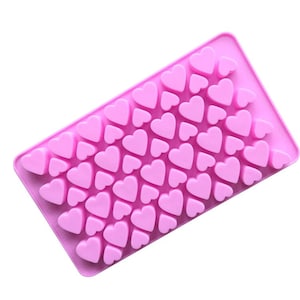 May include: Pink silicone mold with multiple heart-shaped cavities. The mold is designed for making chocolates, candies, or other treats.