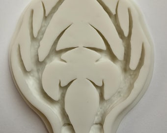 May include: Off-white, oval-shaped mold with a detailed, symmetrical design. The mold features a central, elongated shape with branching, vein-like patterns extending outwards. The design is raised, creating a textured surface. The mold is likely for crafting or decorative purposes.