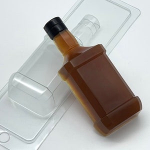 Puede incluir: Un molde de plástico transparente con forma de botella de licor. El molde está lleno de un líquido marrón que se asemeja al whisky.