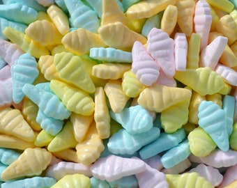 May include: A close-up shot of pastel-colored ice cream cone-shaped candies. The candies are in shades of yellow, blue, and pink. The candies are small and have a textured surface, resembling miniature ice cream cones.
