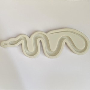 Peut inclure: Un moule en silicone blanc en forme de serpent. Le moule a une surface texturée pour créer un design de serpent détaillé.