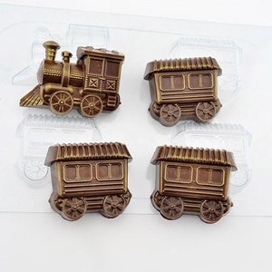 Puede incluir: Un juego de cinco moldes de chocolate para hacer caramelos con forma de tren. Los moldes son de plástico transparente y presentan una locomotora y cuatro vagones.