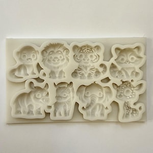 Könnte beinhalten: Eine weiße Silikonform mit acht niedlichen Tierformen: ein Affe, ein Löwe, ein Tiger, ein Waschbär, ein Nashorn, ein Zebra, ein Elefant und eine Giraffe. Ideal zum Basteln oder Backen, perfekt für Tier-Motto-Dekorationen oder Leckereien.
