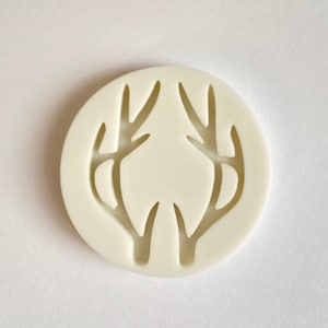 May include: White silicone mold with a deer antler design. The mold is round and has a smooth surface.